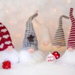 Four christmas gnomes in hats with a christmas bauble that reads merry xmas